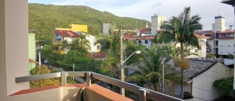A balcony with a view of a residential area, including houses and a hill in the background.