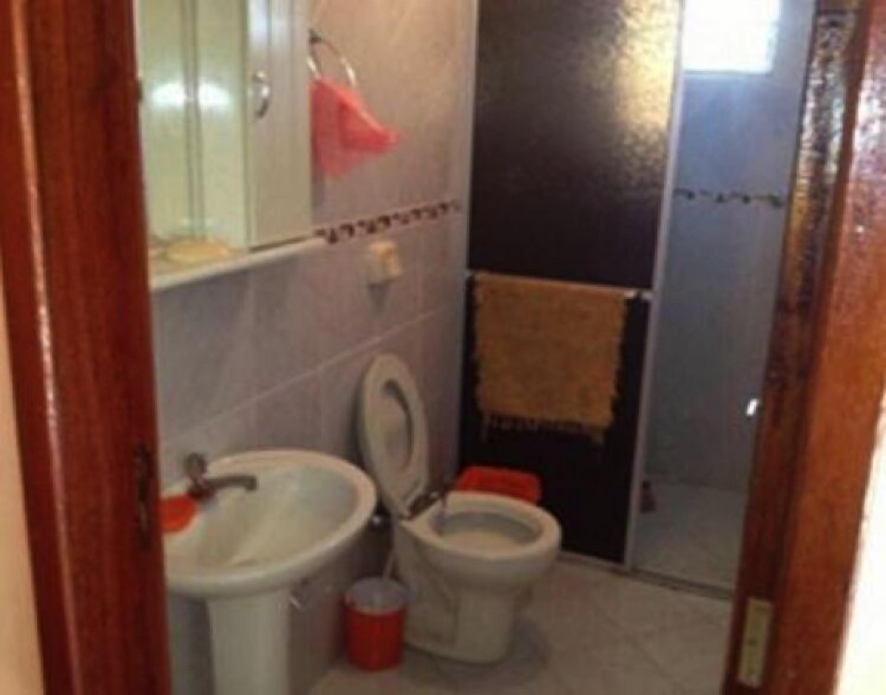 Et lille badeværelse med toilet, vask og et håndklæde hængende på væggen.