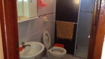 Et lille badeværelse med toilet, vask og et håndklæde hængende på væggen.