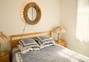 A bedroom with a wooden bed, two bedside lamps, a mirror with lights, and a window with curtains. - Opulent Villa with newly renovated heated pool. 5 minute drive to center (Saint-Rémy-de-Provence)