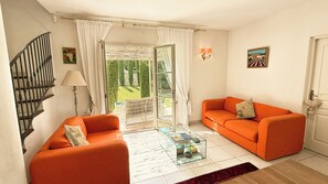 A living room with a staircase, a glass coffee table, and a view of a garden through an open door. - Opulent Villa with newly renovated heated pool. 5 minute drive to center (Saint-Rémy-de-Provence)