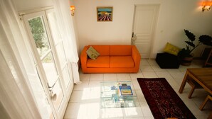 A room with a sofa, a glass coffee table with books, a door, and a wall-mounted painting. - Opulent Villa with newly renovated heated pool. 5 minute drive to center (Saint-Rémy-de-Provence)