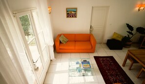 A room with a sofa, a glass coffee table with books, a door, and a wall-mounted painting. - Opulent Villa with newly renovated heated pool. 5 minute drive to center (Saint-Rémy-de-Provence)