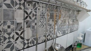 A kitchen with a tiled backsplash featuring geometric patterns, a stainless steel utensil rack, a sink, and a soap dispenser.