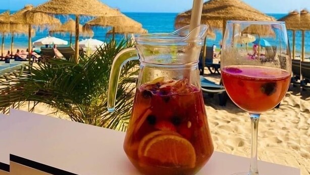 Vista de la playa con una mesa dispuesta, que incluye una jofaina y una copa de vino.