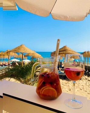 A beach view with a table setting including a pitcher and a wine glass. - Stunning Modern 2bed Apartment! GroundFloor Pool Central Location AirCon 2Patios (albufeira)