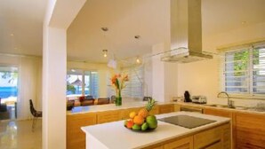 Una cocina moderna con armarios de madera, una isla central con fruta y vistas al océano.