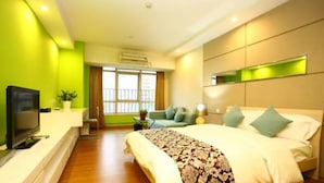 A modern hotel room with a large bed, a flat-screen TV, a sofa, and a small table. - F&H Apartment Guangzhou Wales Branch (Guangzhou)