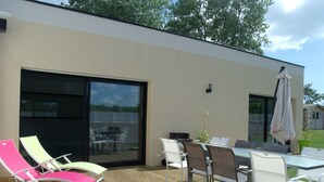 An outdoor patio with a table and chairs, a sliding glass door, and a wooden deck.