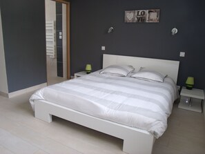 A modern bedroom with a large bed, two bedside tables, and a wall-mounted light fixture.