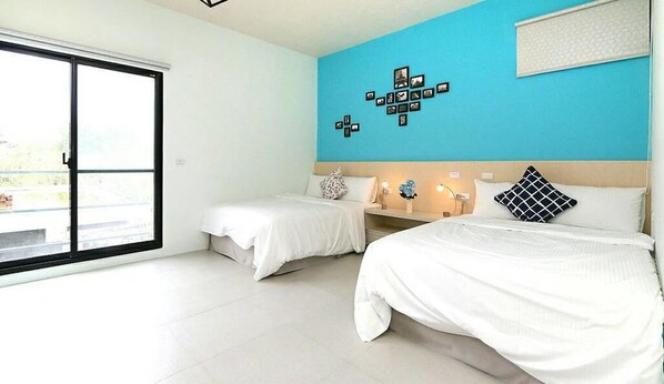 A hotel room with two beds, a large window, and a blue accent wall. - Happiness 210 (Dongshan)