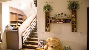 A cozy living area with a large teddy bear, a staircase, and shelves with decorative items. - Happiness 210 (Dongshan)