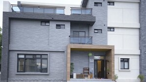 A modern multi-story building with a grey stone facade, large windows, and a balcony. - Happiness 210 (Dongshan)