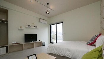 A modern bedroom with a large bed, a television, and a window.