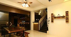 A modern interior with a dining area, staircase, and shelving with decorative items. - Happiness 210 (Dongshan)