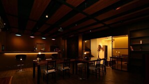 A dimly lit restaurant with wooden beams on the ceiling, a bar area, and several tables and chairs. - Happiness 210 (Dongshan)
