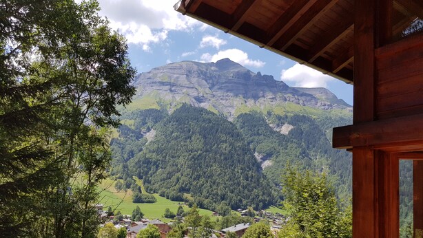 A wooden balcony overlooking a mountainous landscape with a village below.