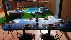 A dining table set for four with a pool and lounge chairs in the background.