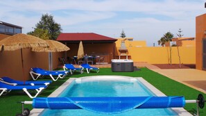 A swimming pool with blue lounge chairs and a hot tub, surrounded by a patio area with a barbecue grill. - beautiful villa with heated pool, outdoor hot tub, free wifi (Antigua)