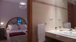 A hotel room with a bed, a large mirror, a bathroom with a sink, and a chandelier. - beautiful villa with heated pool, outdoor hot tub, free wifi (Antigua)