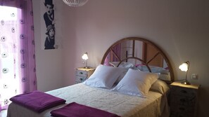 A bed with a wooden headboard, two bedside tables with lamps, a window with curtains, and a poster on the wall. - beautiful villa with heated pool, outdoor hot tub, free wifi (Antigua)