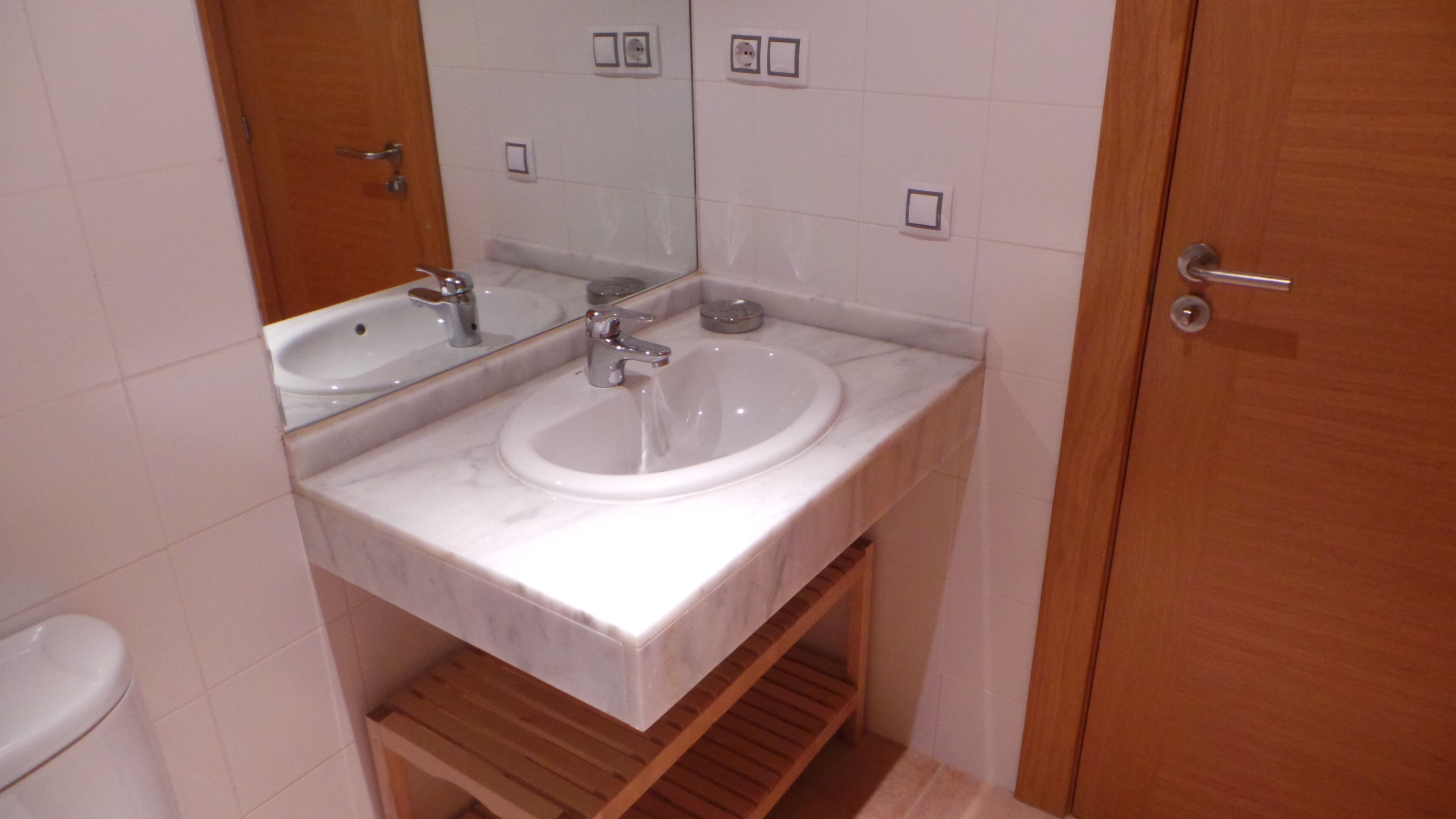 A bathroom with two sinks, a mirror, and a wooden shelf.