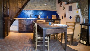 Una cocina rústica con una mesa y sillas de madera, un salpicadero azul y una pared de piedra.