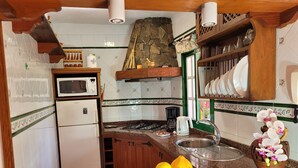 A kitchen with a refrigerator, microwave, stove, sink, and a bowl of lemons and bananas.