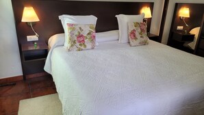 A neatly made bed with floral pillows, a dark headboard, and bedside lamps.