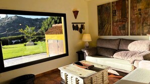 Un salon avec une grande fenêtre, un canapé, une lampe et un élément décoratif mural.