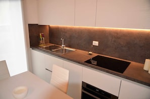 A modern kitchen with a stainless steel sink, a built-in oven, and a countertop with a light under-cabinet.