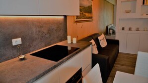 Een moderne keuken met een ingebouwde kookplaat, witte kastjes en een zwart aanrecht.
