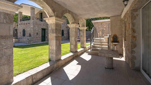 Un edificio de piedra con arcos, un patio cubierto de césped y una escalera que conduce a un nivel superior.