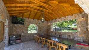 A stone-walled outdoor dining area with a wooden ceiling, stone floor, and a large table with chairs. - Villa Marchelina Grubine - Beautiful stone villa with 2 pools (Grubine)