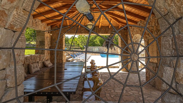 A covered outdoor seating area with stone walls and a wooden ceiling, overlooking a swimming pool. - Villa Marchelina Grubine - Beautiful stone villa with 2 pools (Grubine)