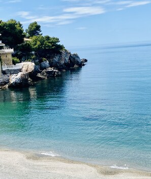 A coastal scene with clear blue water, rocky outcrops, and a building with a white fence. - Casa Mare Nostrum: Chic Villa, Heated Pool & best bay Views (Almuñécar)