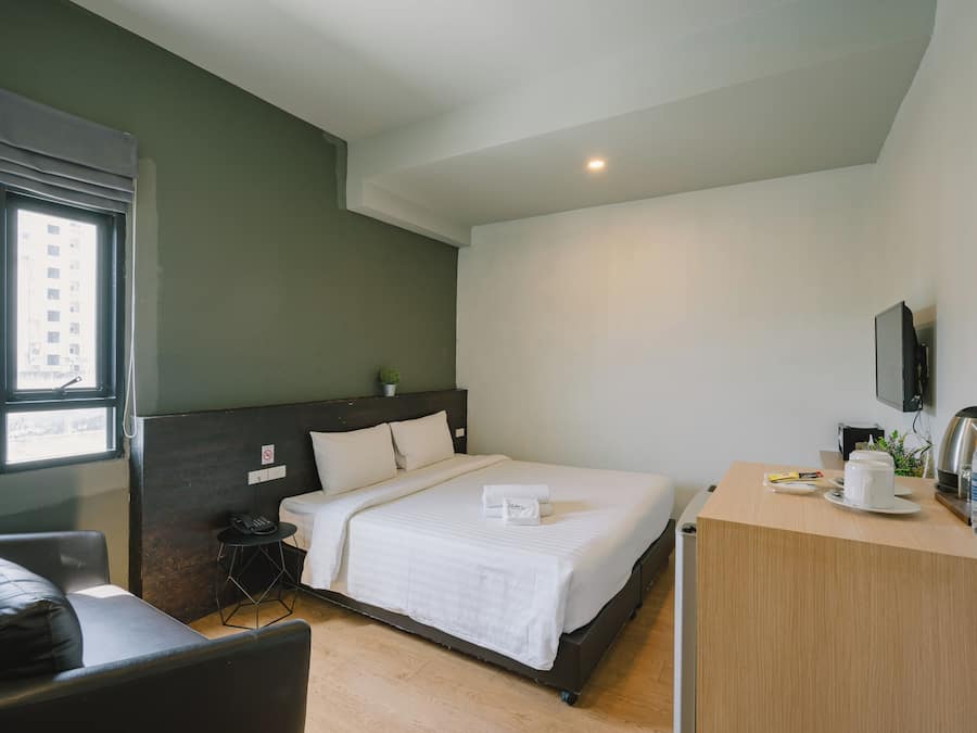 Una habitación de hotel con una cama, mesita de noche y un escritorio pequeño con una silla.