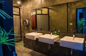 A modern bathroom with three white sinks, a large mirror, and a hand dryer. - The Arbern Hostel x Bistro (Phuket)