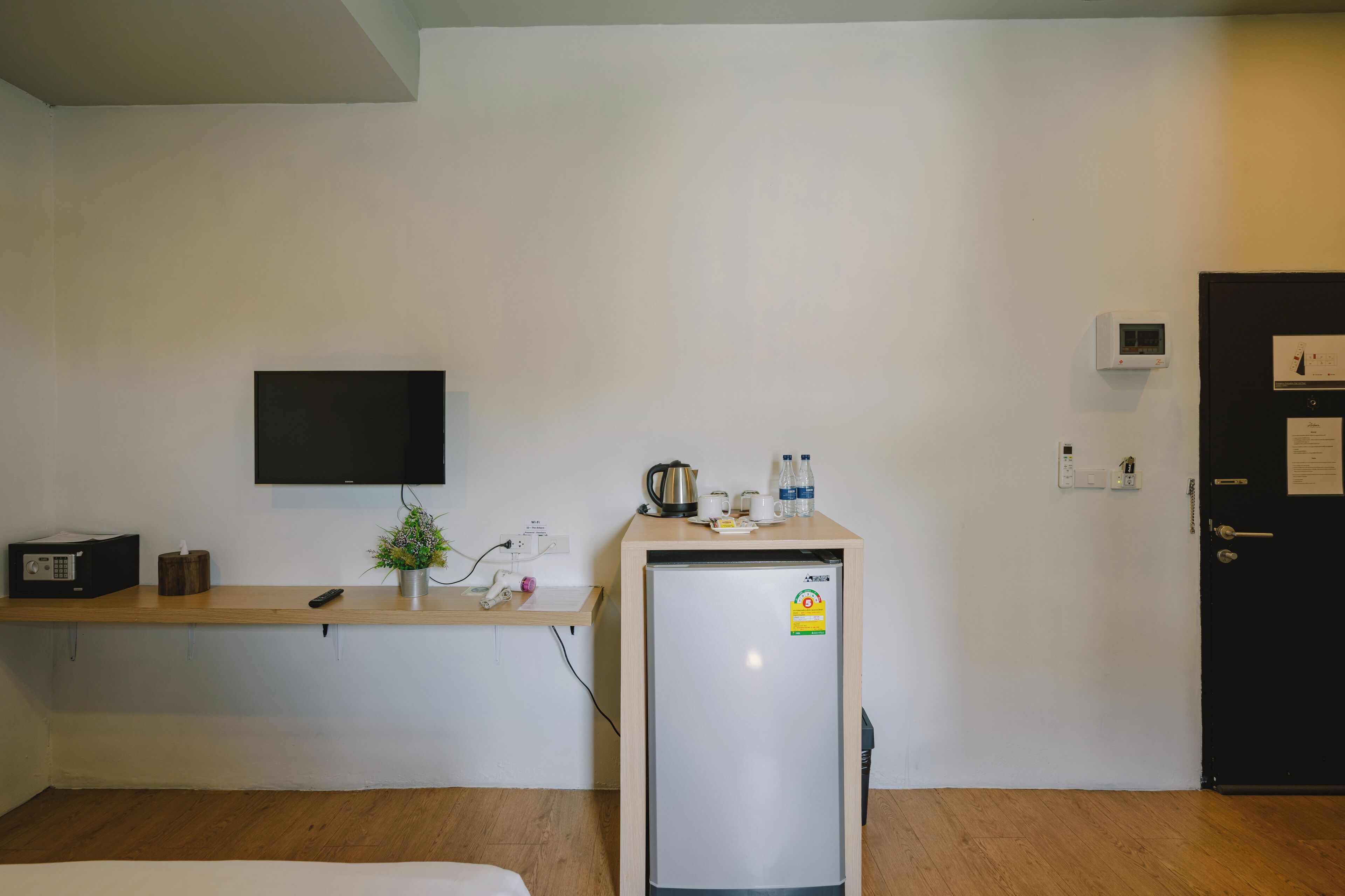 A small kitchenette with a refrigerator, a microwave, a kettle, and a coffee maker on the counter.