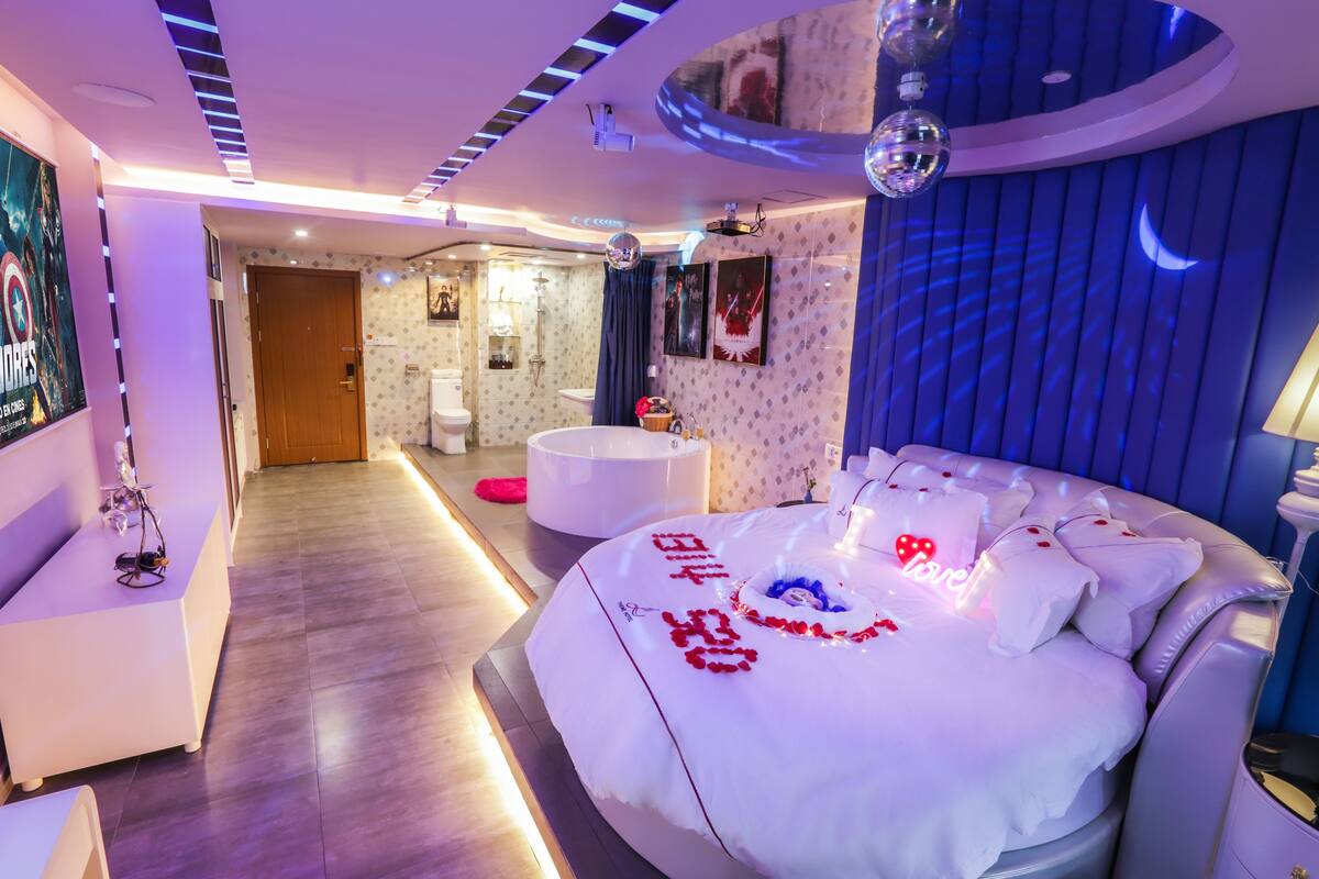 A modern hotel room with a large bed, a sitting area, and a bathroom.