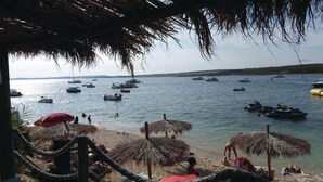 A beach with thatched umbrellas and ropes, boats on the water, and a clear view of the sea. - Villa Morning View, sunrise and relax on southernmost point in Istrian peninsula (Ližnjan)