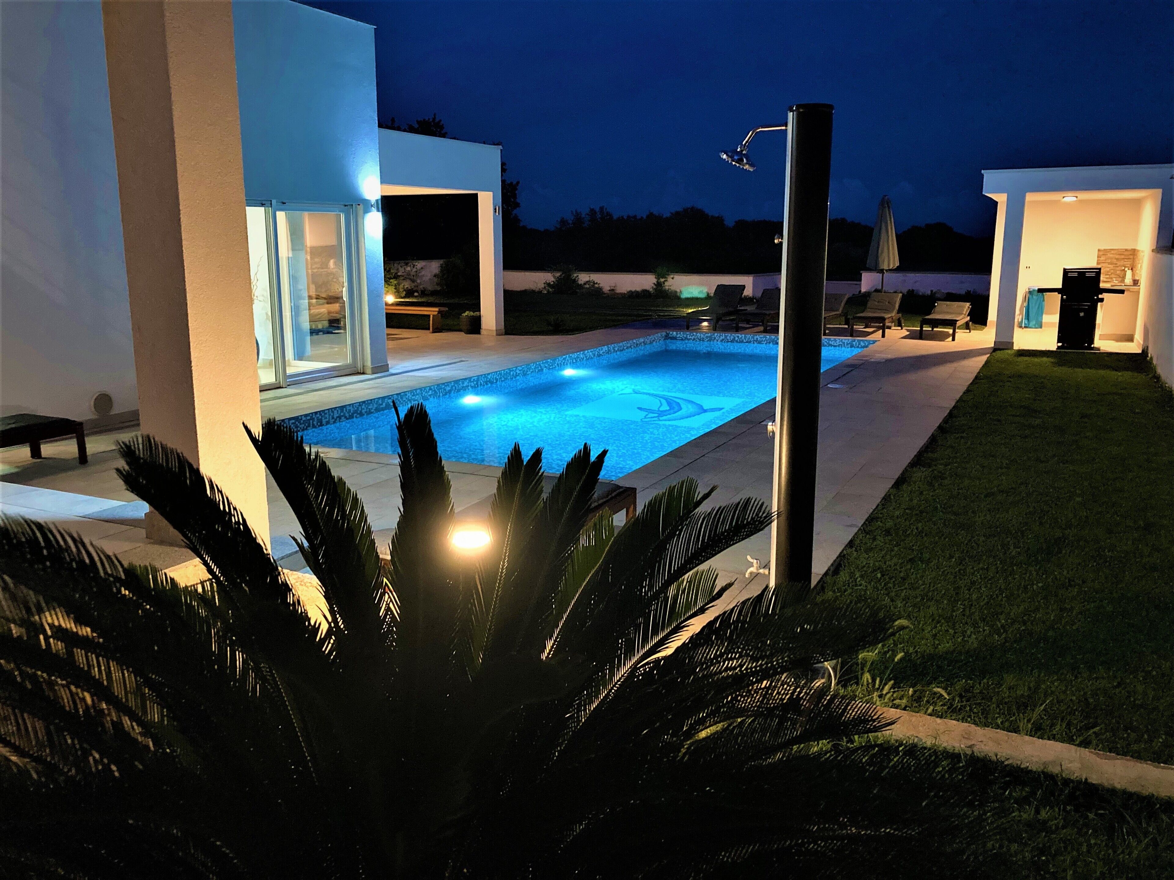 A modern outdoor pool area with a clear view of the pool, surrounding lounge chairs, and a well-maintained lawn.