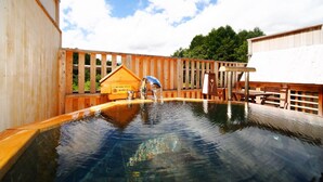 Une terrasse en bois avec un jacuzzi, une clôture en bois et une petite structure en bois portant une enseigne.
