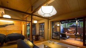 Une pièce chaleureuse aux murs et au plafond en bois, avec un canapé, une table et un hamac à l’extérieur de la porte vitrée.