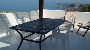 Eine Terrasse mit Tisch und Stühlen mit Blick auf eine Küstenlandschaft.