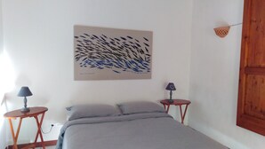 Ein Schlafzimmer mit einem Bett, zwei Nachttischen, einer Lampe auf jedem Tisch, einer Wandlampe und einer Holztür.