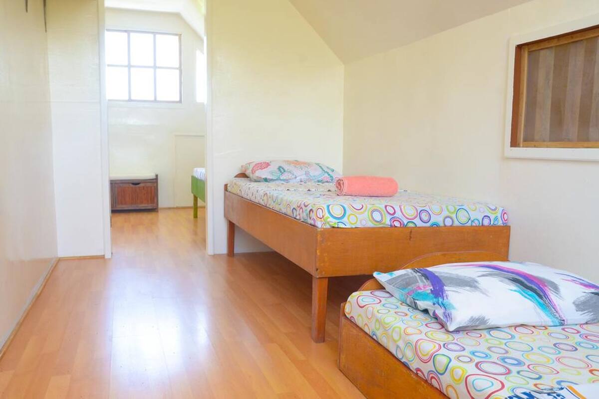 A bedroom with two beds, wooden flooring, and a window.