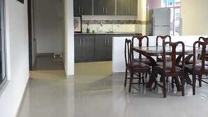 A spacious kitchen with dark cabinets, a central island, and a dining area with wooden chairs.