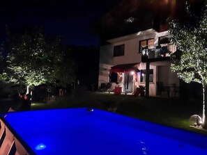 Enjoy a refreshing swim in the pool surrounded by a beautifully manicured lawn and lush trees.