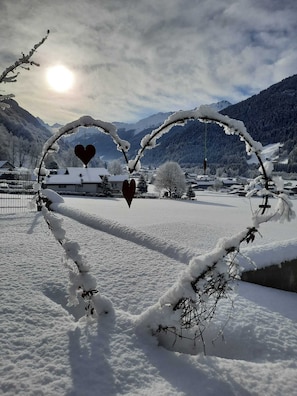 Experience the serene beauty of a snow-covered landscape with a heart-shaped snow sculpture set against a backdrop of snow-covered houses and mountains.